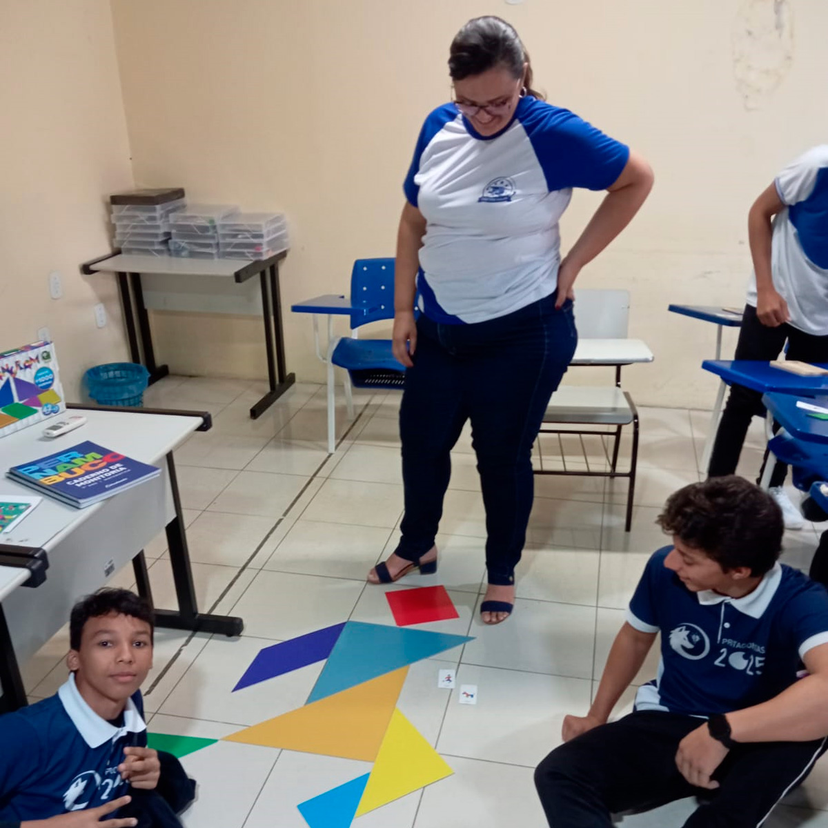 Alunos montando origami obervado por monitora